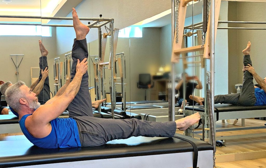 Man doing pilates exercise – the Double Leg Pull – using a mat and no other equipment.